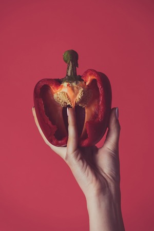 paprika in hand of girl on red background, heartの写真素材