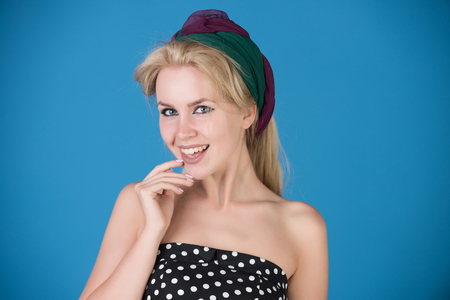 girl smiling with blonde hair, fashionable makeup and turban on head on blue background, beauty and fashion, pin up, retro and vintageの写真素材