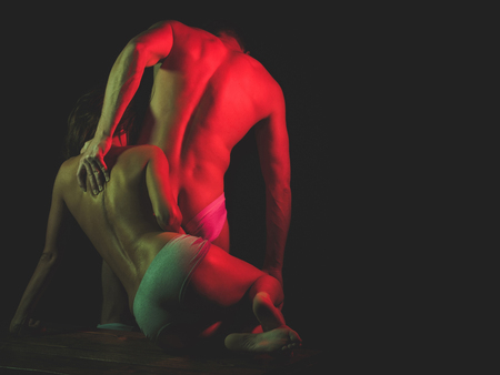 boyfriend and girlfriend with naked back and chest in white underwear pants in red light on black background, passion and couple in love, foreplay and seduction, tenderness and affection, bisexualの写真素材