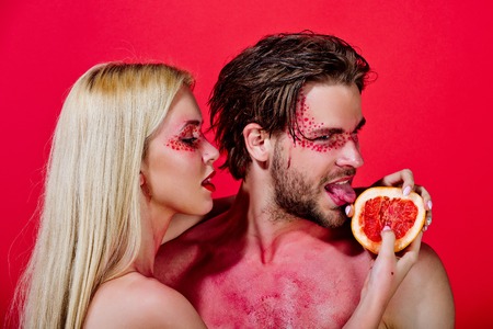 couple of woman and man with creative fashionable makeup on face hold grapefruit fruit on red background, beauty and fashion, allergy, healthcare and vitamin, vegetarian and dietingの写真素材