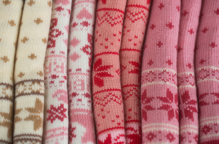 Knits or knitted collection with snowflake pattern rolled on colorful woolen background. Knitting and knitwear. Fashion. Warm winter clothesの写真素材