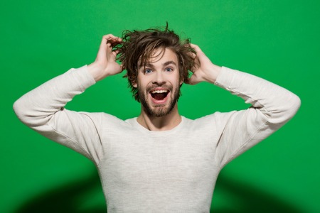 happy man with long stylish uncombed hair and smiling bearded man on green background, morning and barbershop fashionの写真素材