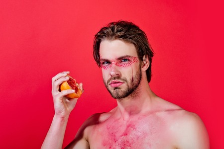 half of a juicy grapefruit in hand of man on red background, vitaminの写真素材