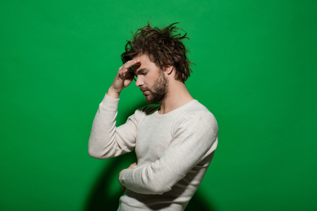 tired guy or handsome man with beard and stylish hair in white underwear on green background, morning and fashion, headacheの写真素材