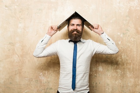man or hipster with long beard and stylish hair on happy face in tie and white shirt hold laptop on textured beige background, digital marketing and business, agile business, businessmanの写真素材