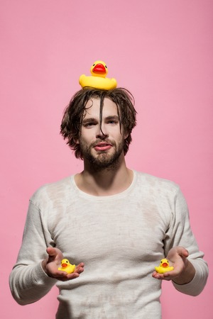 man with duckling toy in bath or shower with wet hair on pink backgroundの写真素材