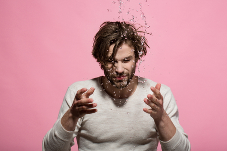 man washing face with water drops in morning. guy with long hair refreshing in underwear on pink background, hygiene and skincare, health and wakeup, everyday life, barbershopの写真素材
