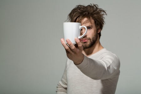 cup of tea or coffee at man with uncombed hair in underwear on grey background, morning refreshment and drink, energy, copy spaceの写真素材