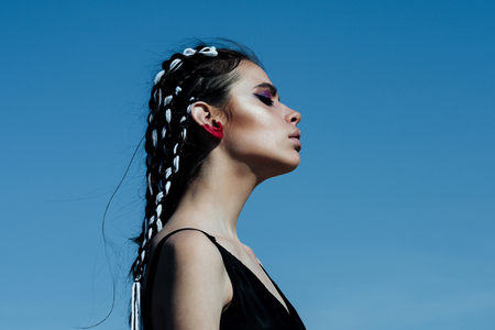 Woman has stylish hair with rope. Girl with fashionable makeup on blue sky background. Beauty and fashion. Cosmetics and skincare. Hairdresser and barber.の写真素材