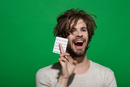 Treatment and hypnotic tablet. Guy hold dieting pill and vitamin. Man with pills in blister pack. Drug and antidepressant. Health and medicine.の写真素材