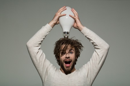 guy has an idea. Power and business success. Energy and electricity concept. Young surprised guy. Man with big lamp on head.の写真素材