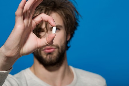 Man with pill in hand. Health and medicine. Treatment and hypnotic tablet. Guy hold dieting pill and vitamin. Drug and antidepressant.の写真素材