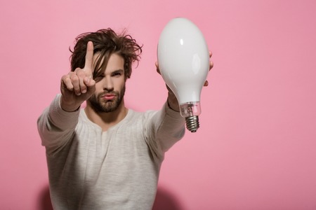 guy has an idea. Man with big lamp. Power and business success. Energy and electricity concept. Young serious guy got an idea, copy spaceの写真素材