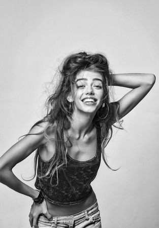 lady or smiling sexy girl with long hair in vest and jeans, has bare belly, black and whiteの写真素材