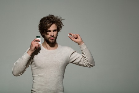 Drug and antidepressant. Health and medicine. Treatment and hypnotic tablet. Guy hold dieting pill and vitamin. Man with pill in plastic jar.の写真素材