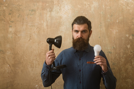 man with long beard hold lamp and bulb in hand on beige backgroundの写真素材