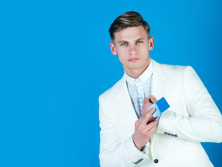 Businessman posing in white jacket and shirt. Banking and saving. Manager wearing casual suit on blue background. Fashion and information concept. Man holding business or bank card, copy spaceの写真素材