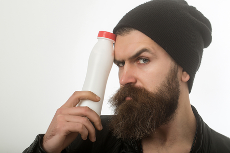 Hipster in hat with yoghurt. Dieting and health. Food and drink. Ecology product and plastic. Man with long beard hold milk bottle.の写真素材