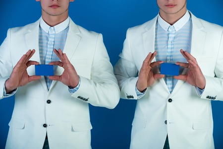 Mens hands holding blank paper cards on blue background. Information and business ethics concept.