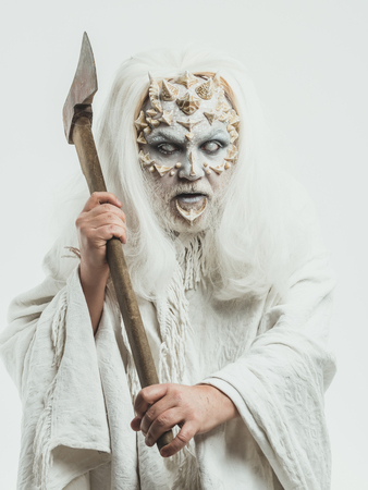 Wizard with long silver hair. Demon with axe in hands on white background. Monster with thorns and beard on face. Man with blind eyes. Horror and death concept.の写真素材