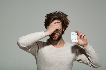 Treatment and hypnotic tablet. Drug and antidepressant. Health and medicine. Guy hold dieting pill and vitamin. Man with pills in blister pack.の写真素材