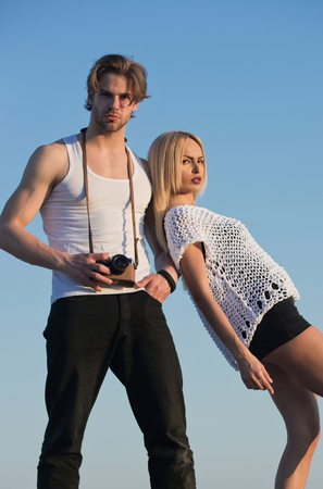 Girl with photographer outdoor. Man with muscular body with girlfriend. Couple in love and romance. Guy with photo camera on athletic chest. Beauty and art fashion.の写真素材