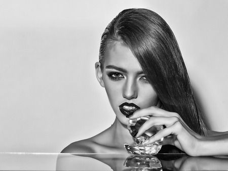 lady with long hair has bright lips with glassy decorative shell with pearl, black and whiteの写真素材