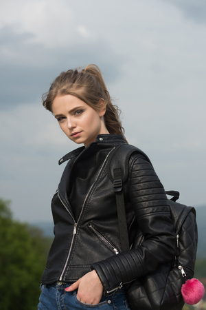 Girl in leather jacket. Sexy woman outdoor. Beauty and fashion. Fashion model on blue sky. Woman with long hair with backpack.の写真素材