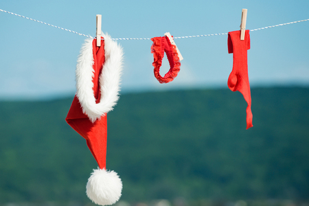 New year costume on blue sky. santa clothes for drying. Xmas red costume on rope with pin. Laundry and dry cleaning. Christmas clothes outdoor.の写真素材