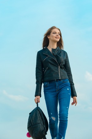 Fashion model on blue sky. Beauty and fashion. Woman with long hair. Sexy woman outdoor. Girl in leather jacket with backpackの写真素材