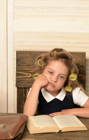 Education and childhood. Little baby secretary in cabinet. Kid reading book. Child play in school. Small girl with curler in hair.の写真素材