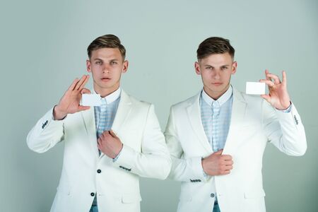 Men holding blank cards on grey background. Businessmen wearing white jackets. Business communication and meeting. Cooperation and partnership. Banking and saving concept.の写真素材