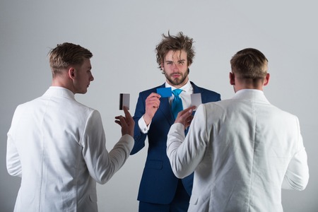 Businessmen exchanging cards on grey background. Group of people facing each other. Men wearing...