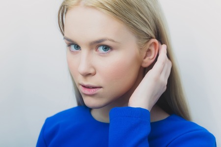 Girl with healthy skin and makeup foundation on face. Pretty woman touching blond long hair with...