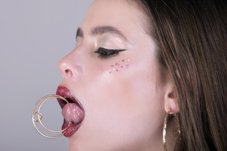 Hairdresser and barber. Beauty salon and fashion. Girl with fashionable makeup. Cosmetics and skincare. Woman has stylish long hair in earrings.の写真素材