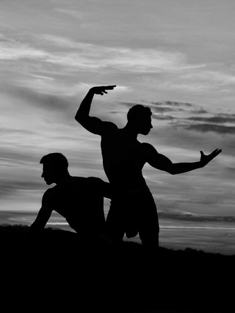 silhouette of men or bodybuilders, athlete people with sexy torso outdoor in sunset sky, black and whiteの写真素材
