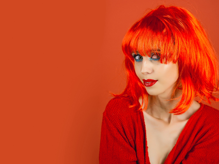 woman with orange hair wig and fashionable makeup has red lips, copy spaceの写真素材