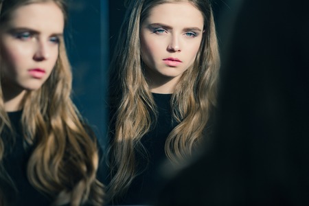 Skincare and salon. Beauty and fashion. Hairdresser and barber. Woman with long hair and pretty face. Girl look at mirror.の写真素材