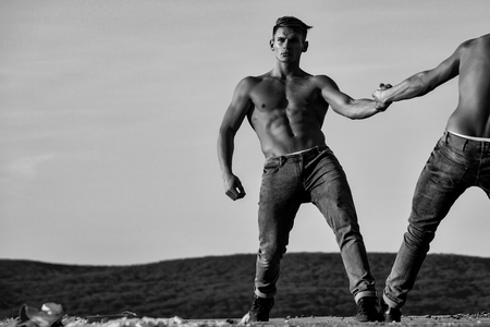 men or bodybuilders, athletes with sexy, muscular torsos with six packs, abs, biceps, triceps wrestling outdoor in mountains on sky, black and whiteの写真素材