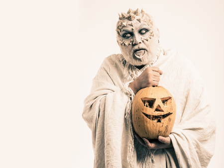 Halloween and horror concept. Demon with silver beard and hair. Monster with thorns on face. Man with orange pumpkin. Wizard with blind eyes on white background, copy spaceの写真素材