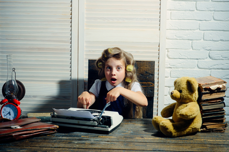 Little baby secretary with bear and book. Kid choose career and typing. Education and childhood. Small girl with curler in hair. Child with briefcase and alarm clock.の写真素材