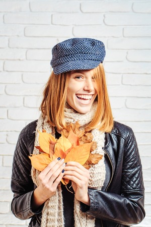 Girl with orange leaves at brick wall. Beauty and fashion. Season and autumn holiday. Woman with...