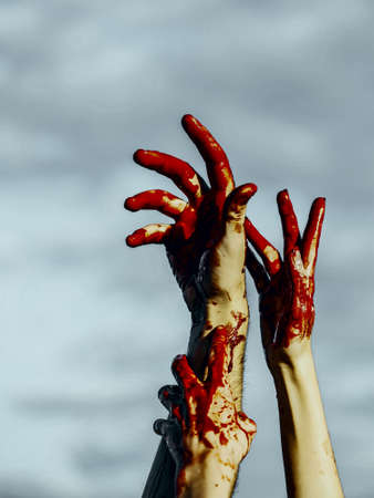 Halloween zombie hands on grey sky background. Bloody hands with red blood stretching up. Maniac or murderer concept. Halloween holiday celebrationの写真素材