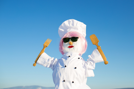 Christmas or xmas decoration. New year snowman chef from snow with hat. Happy holiday and celebration. Winter party and cooking. Snowman cook with wooden spoon and fork.の写真素材