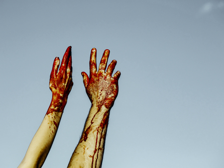 Halloween male and female hands on grey sky background. Two bloody hands bleeding with red blood. Maniac or murderer concept. Halloween holiday celebration, copy spaceの写真素材