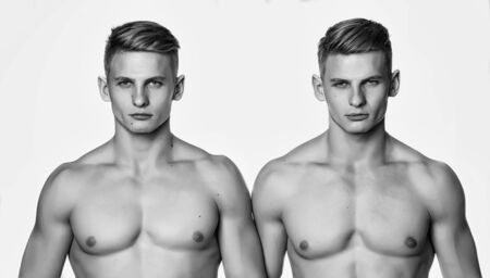 Twins two young men with sexy body and muscular chest stand together isolated on white backgroundの写真素材