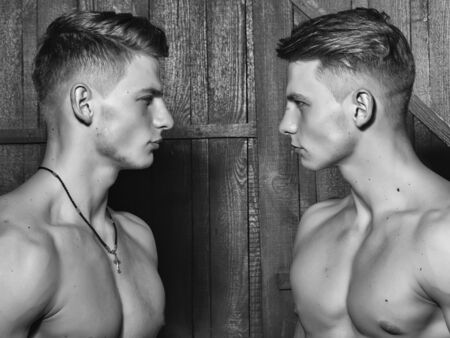 Two young male twins with sexy body and muscular chest standing together in studioの写真素材
