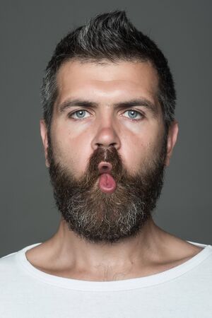 man with long beard on emotional grimace face on grey backgroundの写真素材