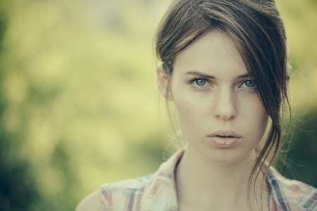Model in plaid shirt on sunny day. Health and beauty. Summer vacation concept. Girl with brunette hair, hairstyle, outdoors. Woman posing on blurred natural background, copy spaceの写真素材