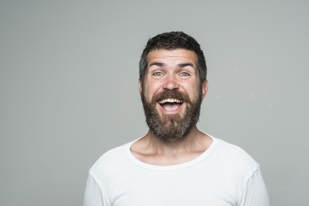 Hipster with happy face. Feeling and emotions. Guy or bearded man on grey background. Barber fashion and beauty. Man with long beard and mustache.の写真素材